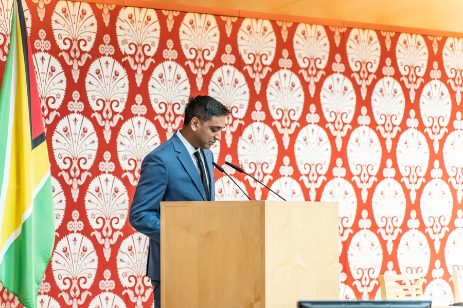 A speaker at the podium between the Canadian and Guyanese flags